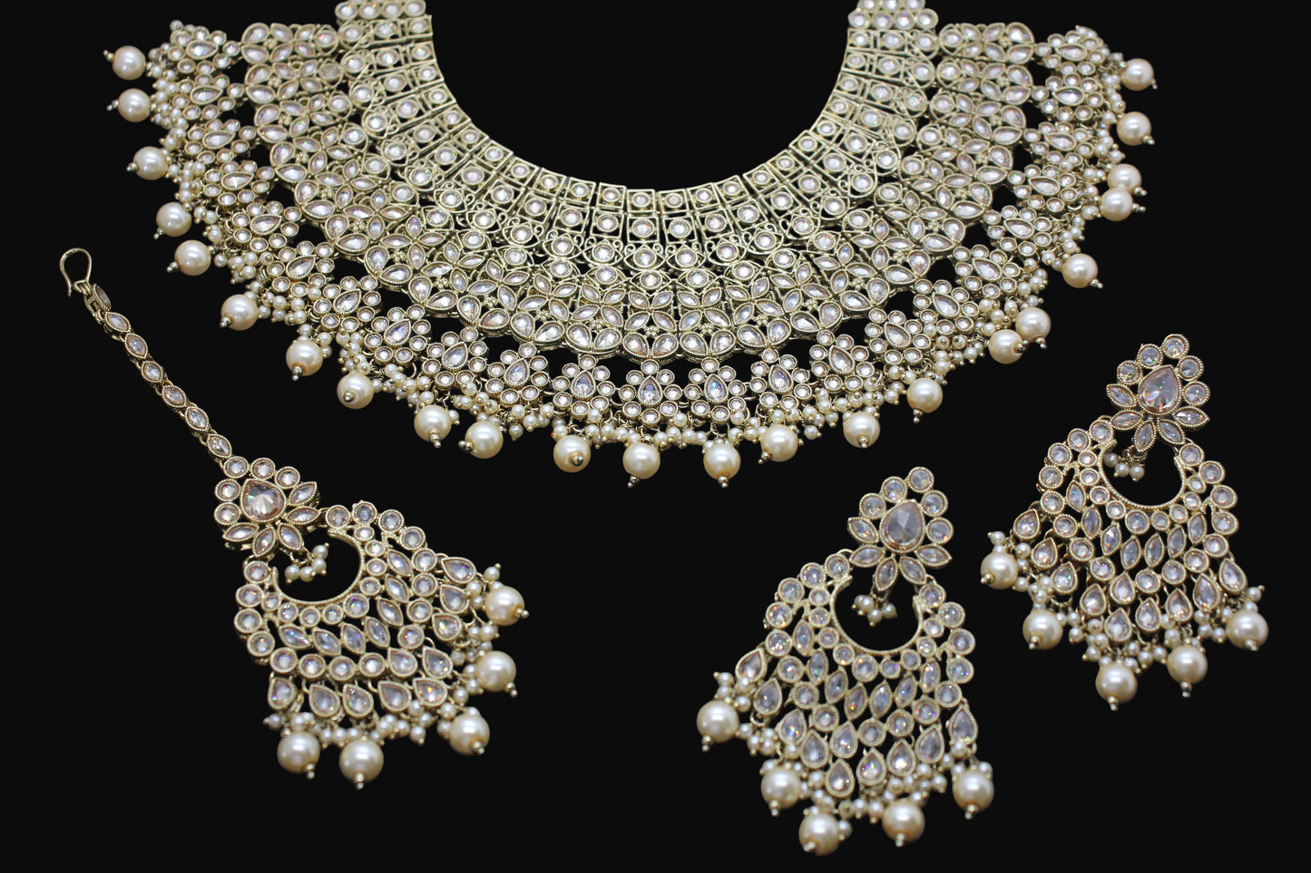 Ornate pearl and crystal jewelry set on a dark background