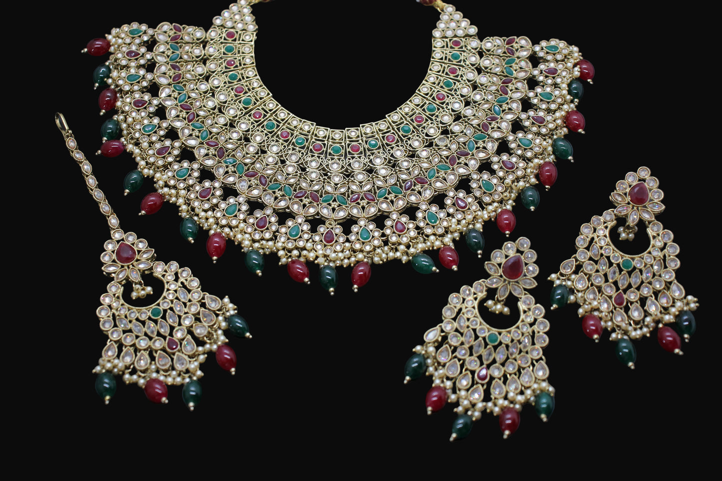 Ornate necklace and earrings set with gemstones on a dark background