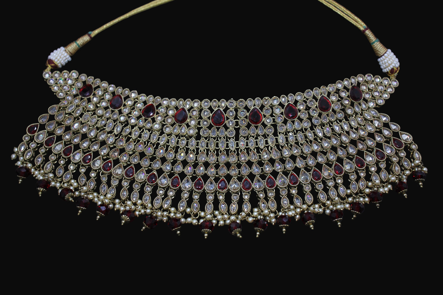 Ornate necklace with pearls and red stones on a dark background