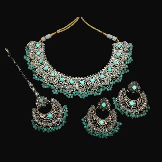 Jewelry set with necklace, earrings, and tikka on a dark background