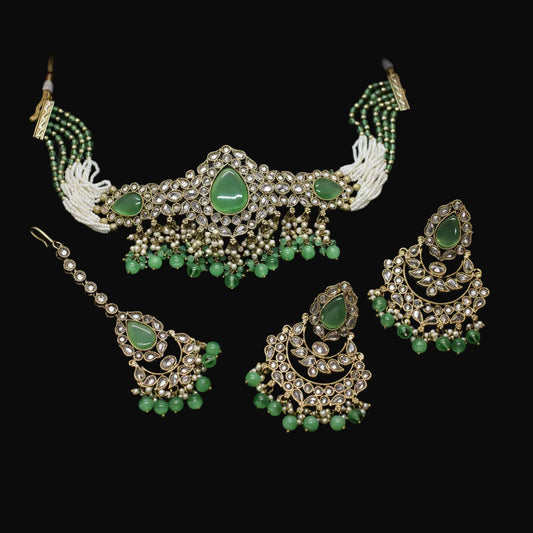 Green and gold jewelry set on a dark background
