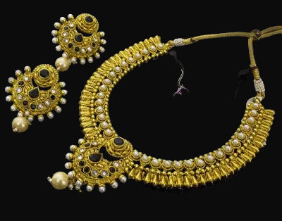 Gold necklace and earrings set with 'SAHELI' branding on a dark background