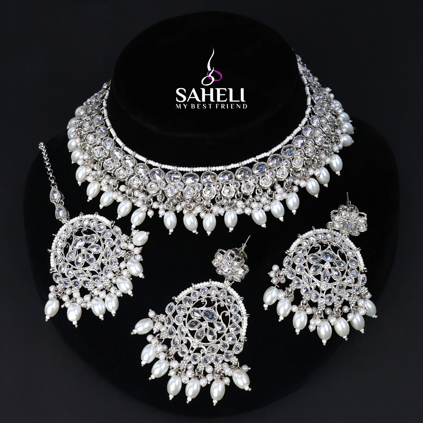 Jewelry set with necklace, earrings, and ring on a black background with 'SAHELI' branding.