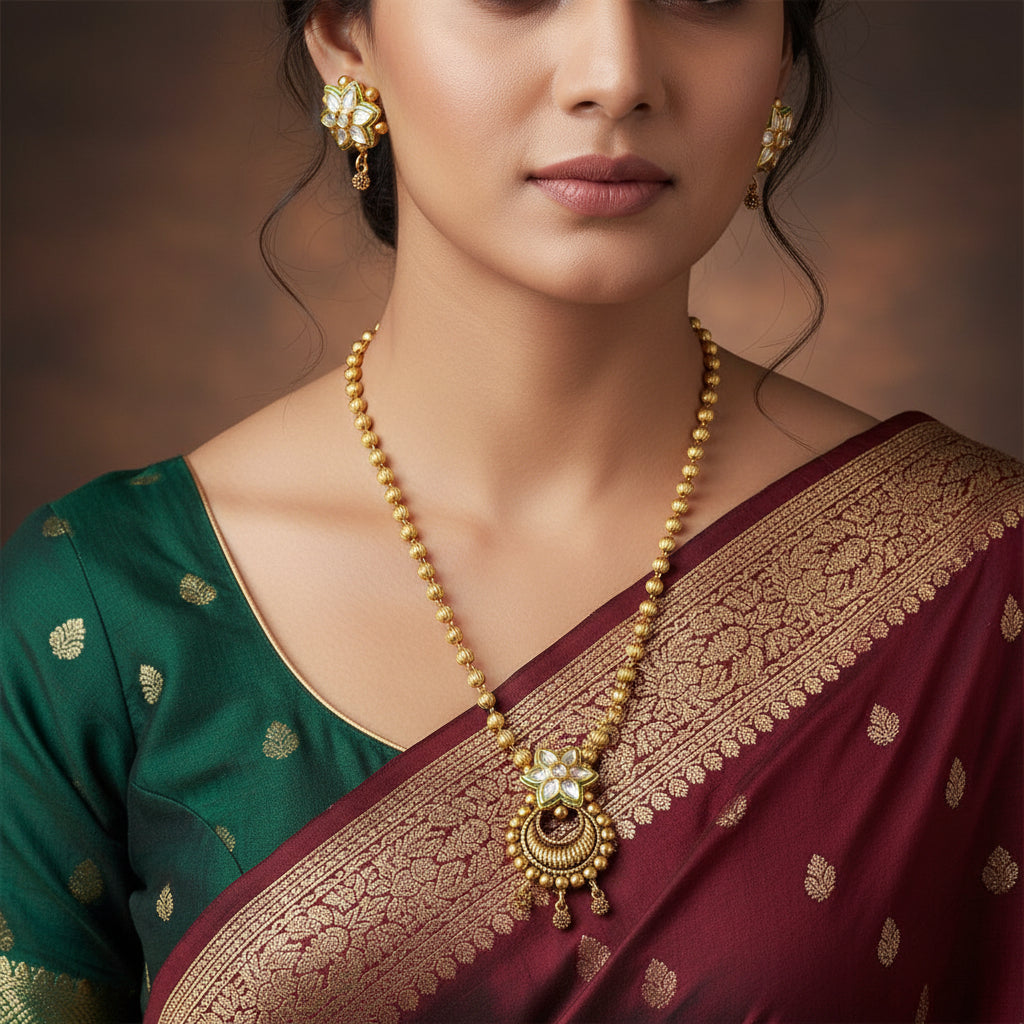 Gold necklace and earrings with floral designs on a gray background, featuring the brand 'SAHELI'.