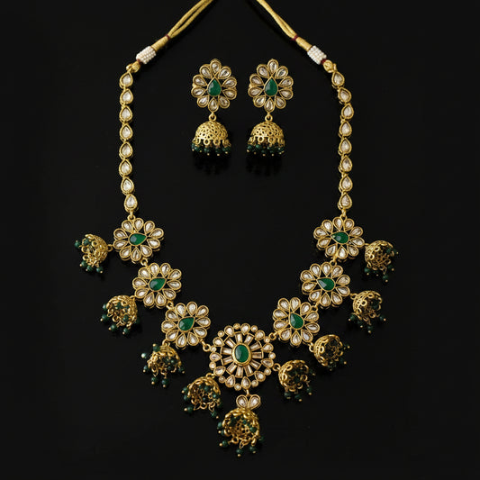 Gold-plated Kundan necklace and matching earrings with green stone accents, displayed on a dark gray background with the SAHELI MY BEST FRIEND logo in the top left corner.