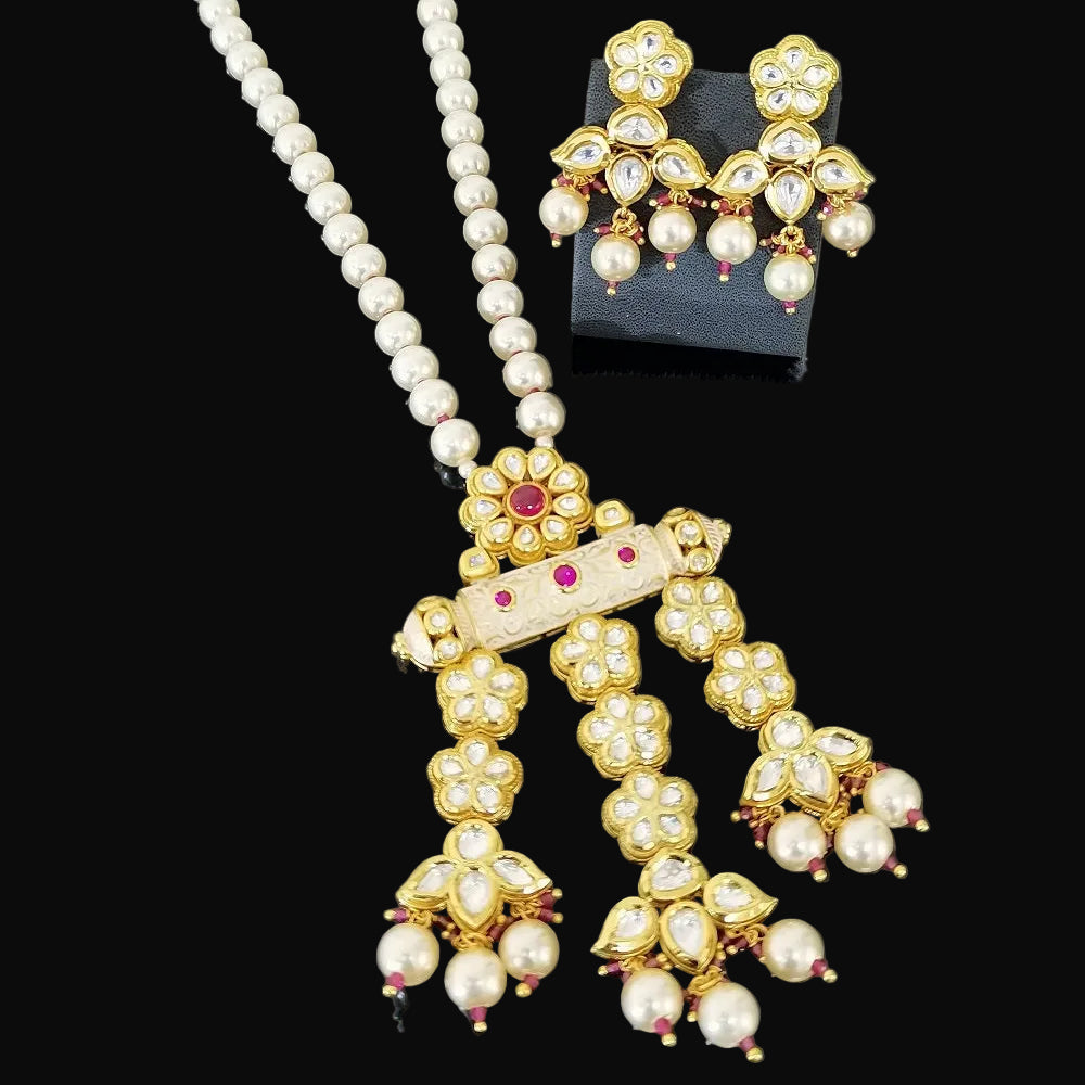 Gold and pearl Indian jewelry set featuring a necklace with a detailed pendant, matching drop earrings, and a black display stand on a dark gray background. The brand logo 'SAHELL MY BEST FRIEND' is visible in the top right.