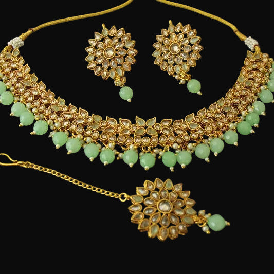 Gold and green jewelry set on a black background