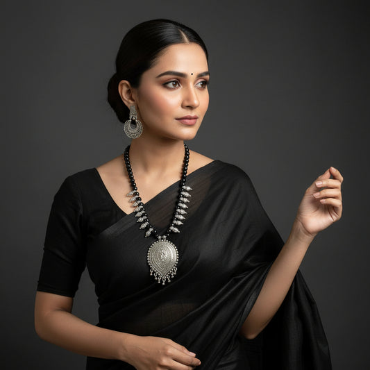 Silver necklace with black beads and matching earrings on a gray background, featuring the brand 'Saheli'.