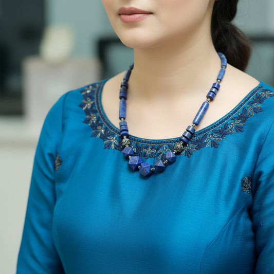 Person wearing a blue beaded necklace in an indoor setting