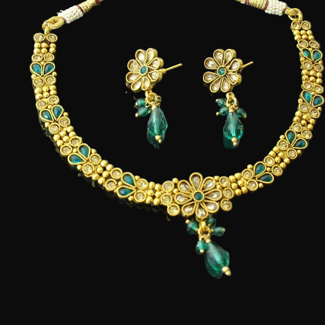 Gold necklace with green beads and matching earrings on a gray background, featuring the brand 'Saheli'.
