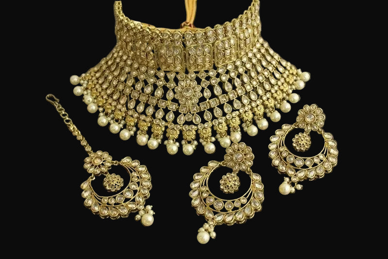 Gold and pearl jewelry set with 'SAHELI' branding on a dark background