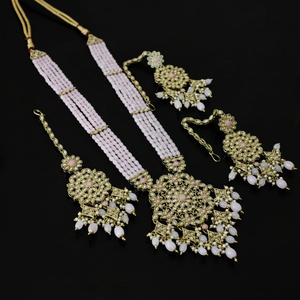 Ornate gold and pink jewelry set on a dark surface