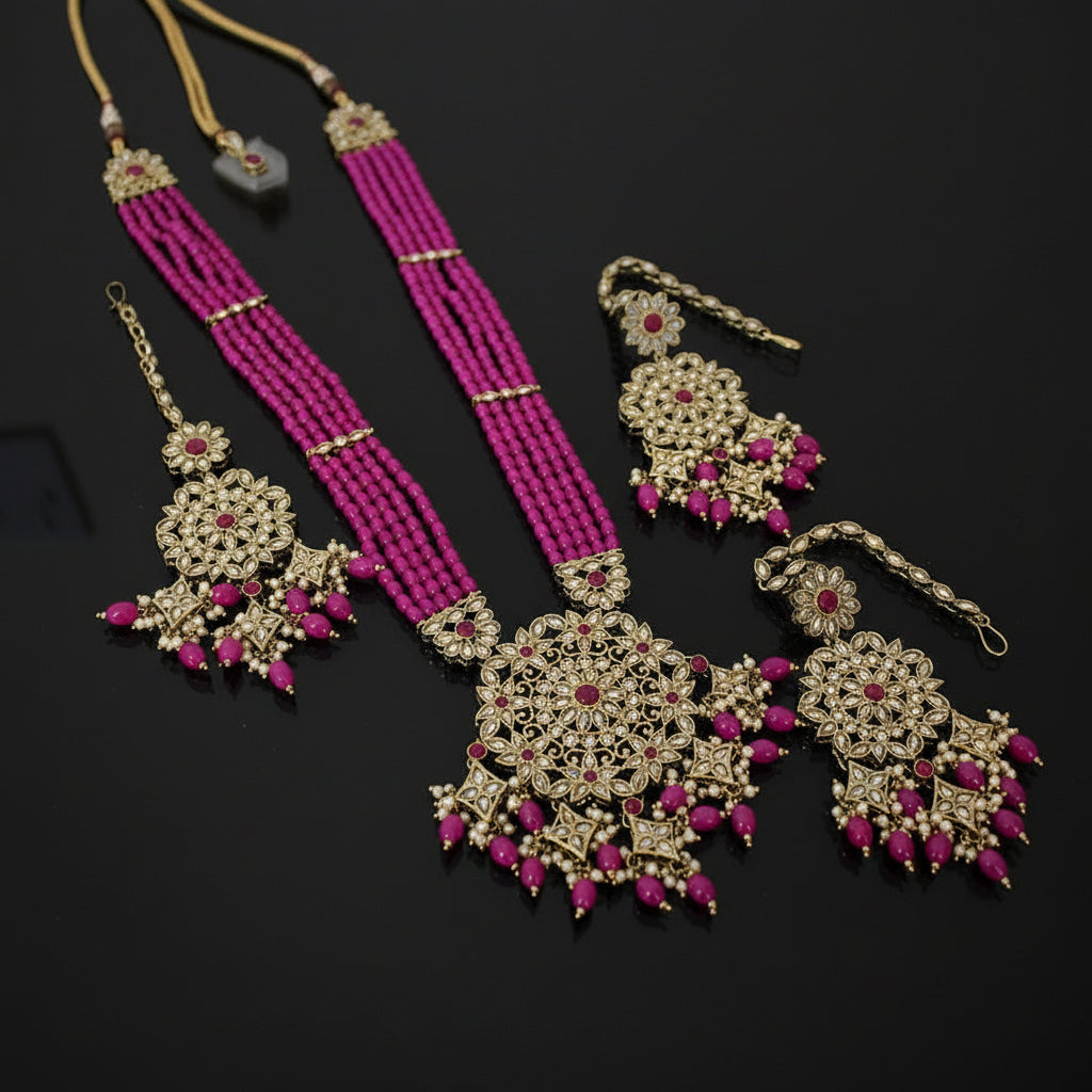 Jewelry set with pink beads and gold accents on a dark background