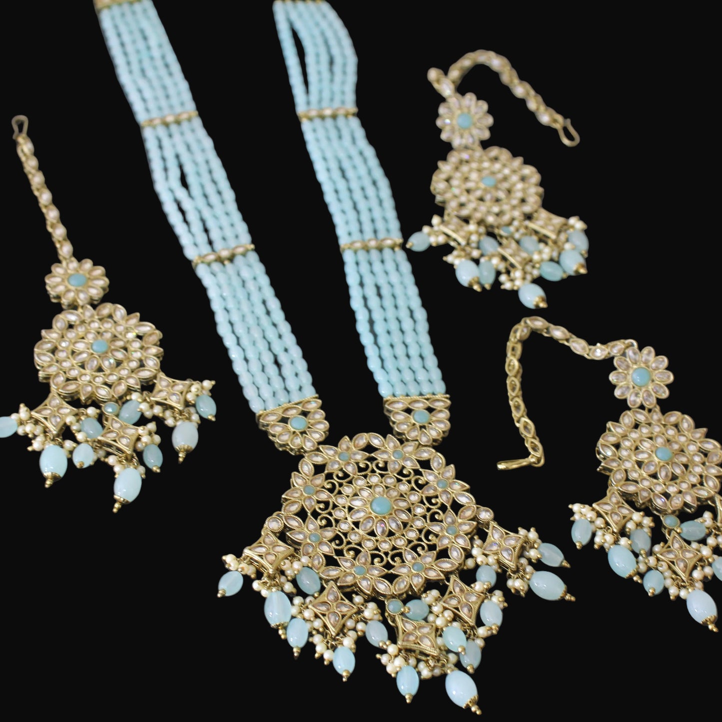 Jewelry set with gold and turquoise necklace, earrings, and headpiece on a dark background