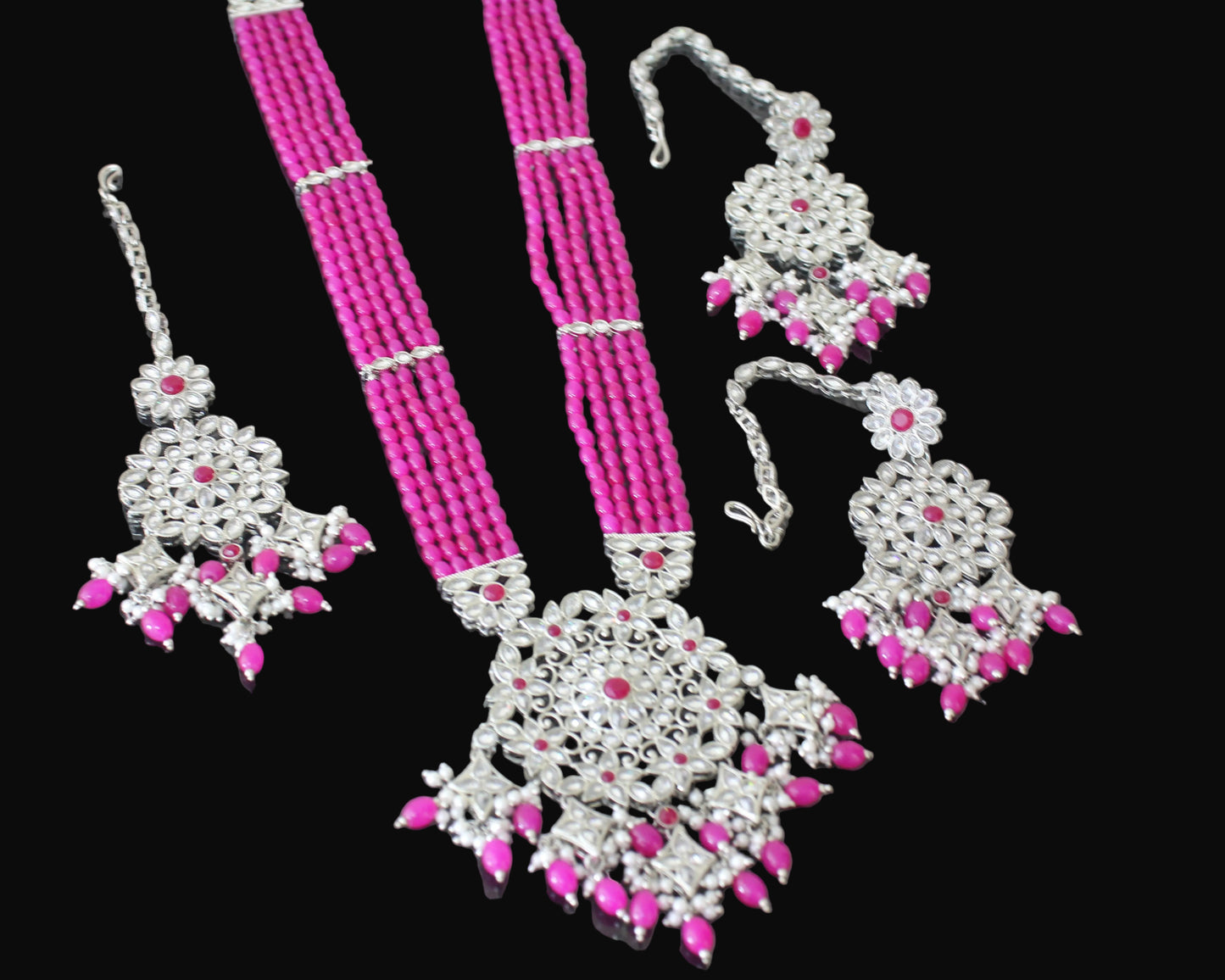 Pink beaded necklace with silver and pink jewelry set on a dark background