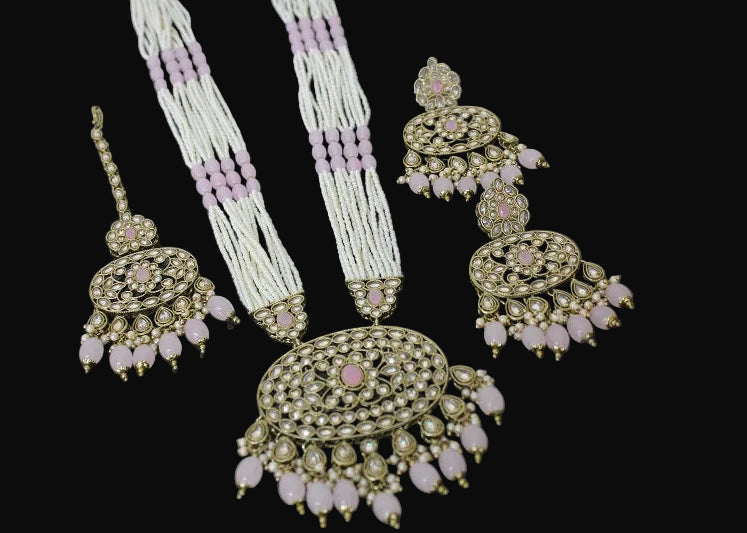 Set of traditional jewelry including necklace, earrings, and pendant on a reflective surface.