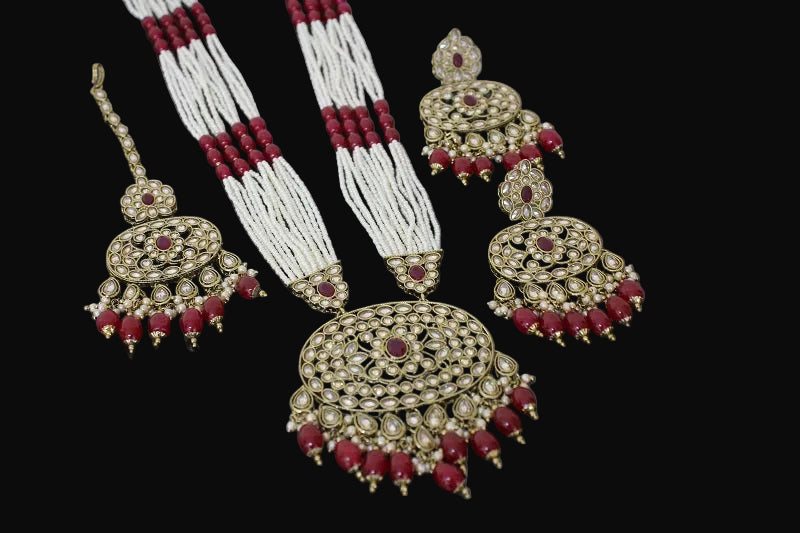 Jewelry set with gold, red, and white elements on a dark background
