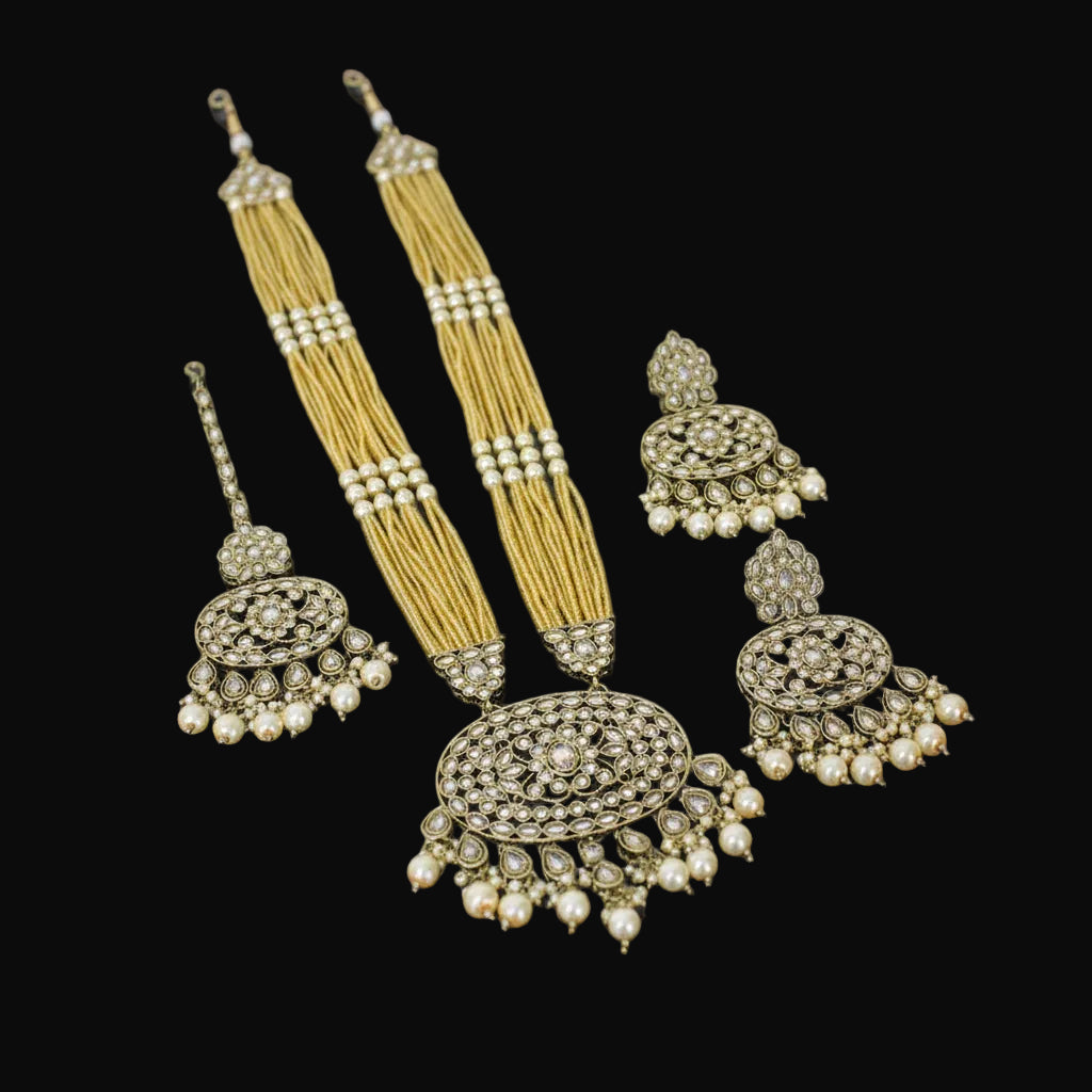 Ornate jewelry set with earrings and a necklace on a dark background