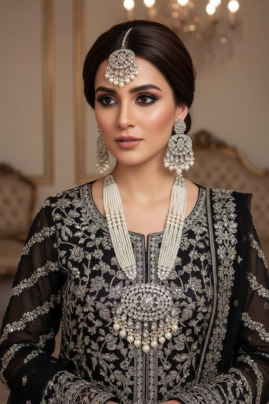 Silver jewelry set with necklaces and earrings on a reflective surface