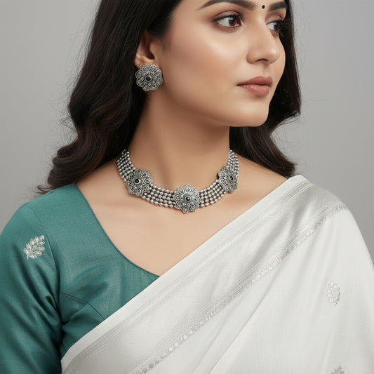 Silver necklace and earrings set on a reflective surface