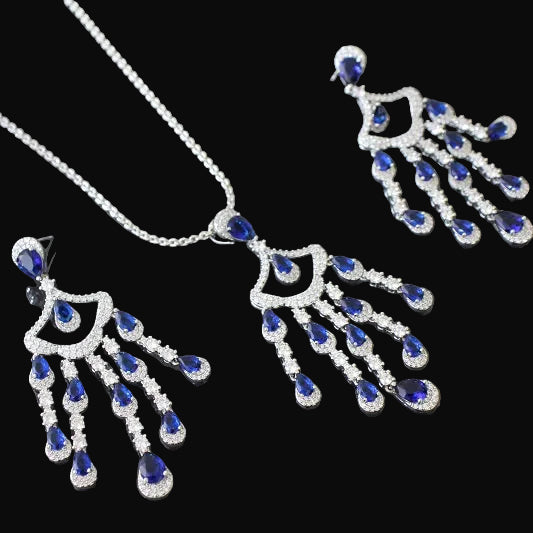 Jewelry set with silver necklaces and earrings featuring blue gemstones on a dark background