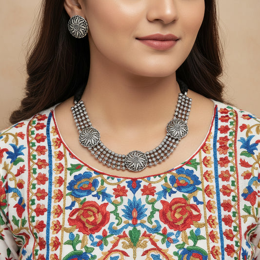 Silver necklace and earrings set on a reflective surface