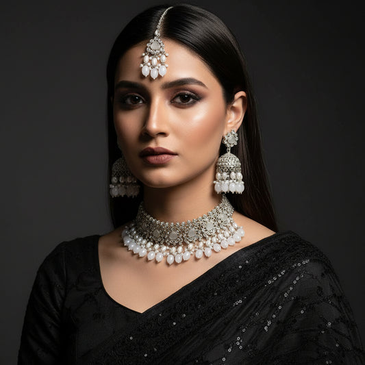 Silver jewelry set including a tiara, earrings, and necklace on a dark background with 'SAHELI' branding.