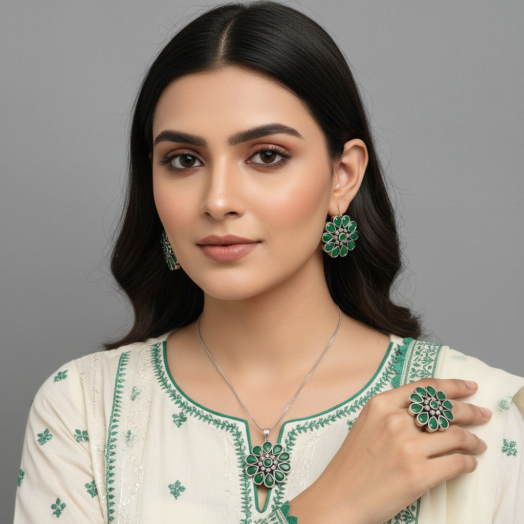 Silver jewelry set with green gemstones on a gray background