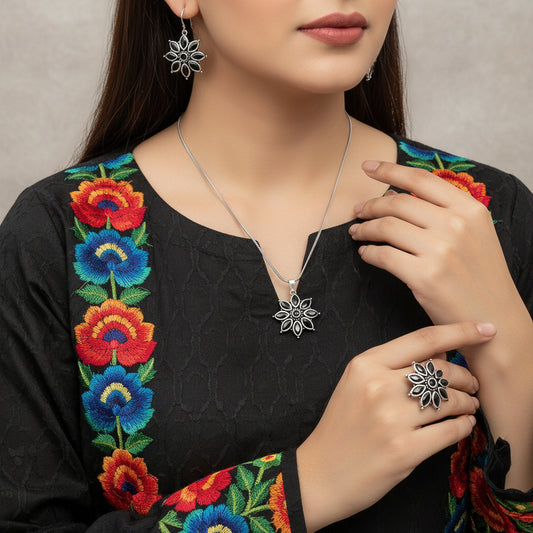 Silver floral necklace and earrings on a gray background