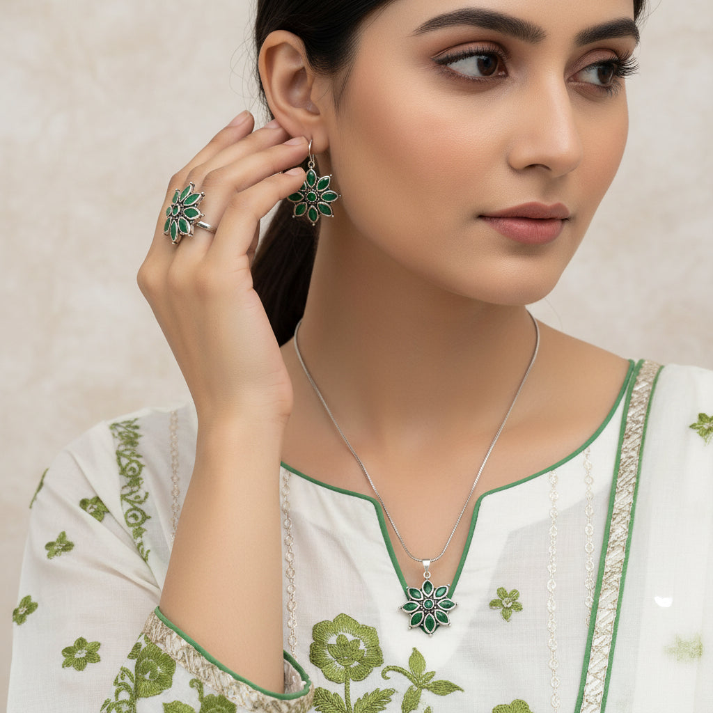Silver jewelry set with green floral designs on a gray background