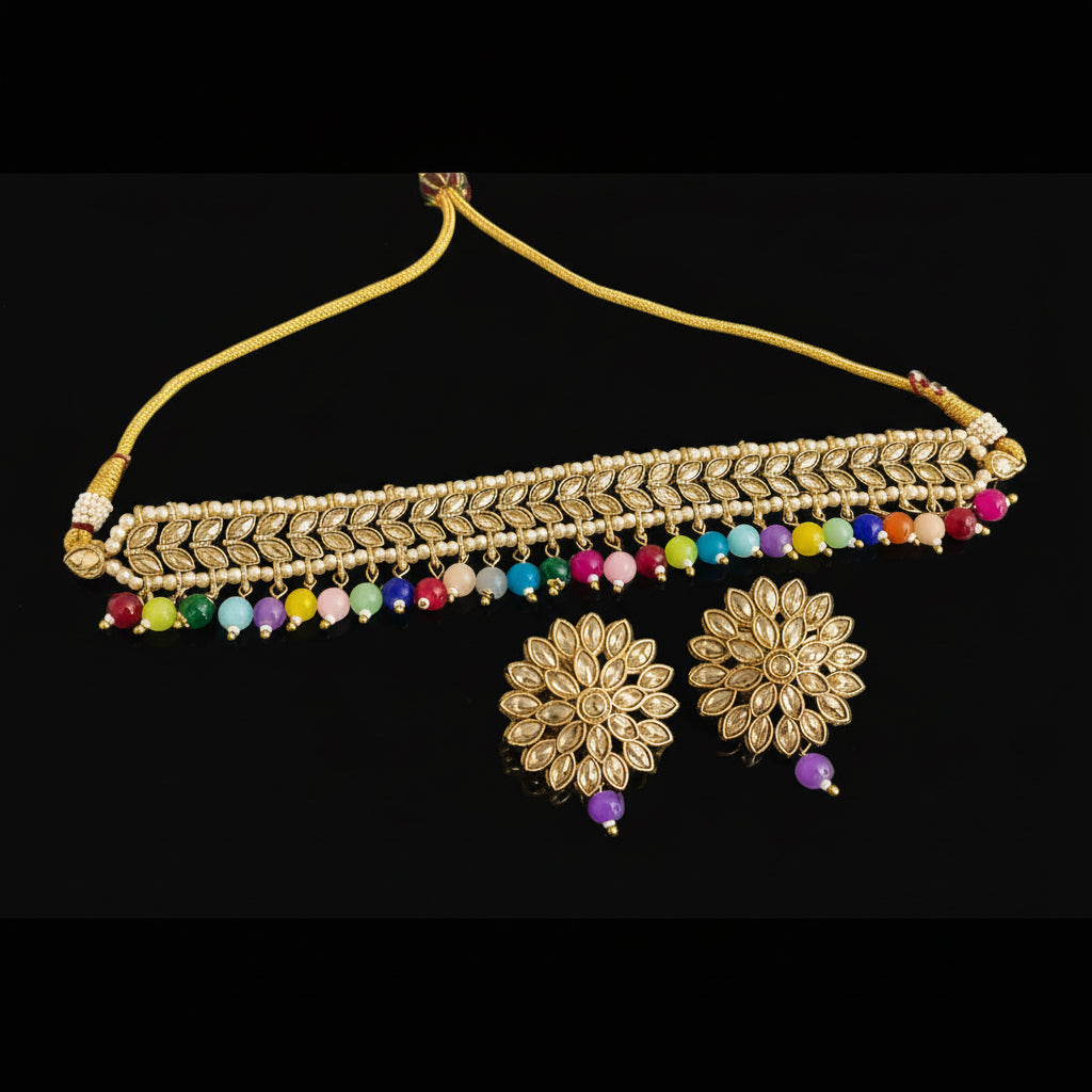 Gold necklace with colorful beads and matching earrings on a dark surface