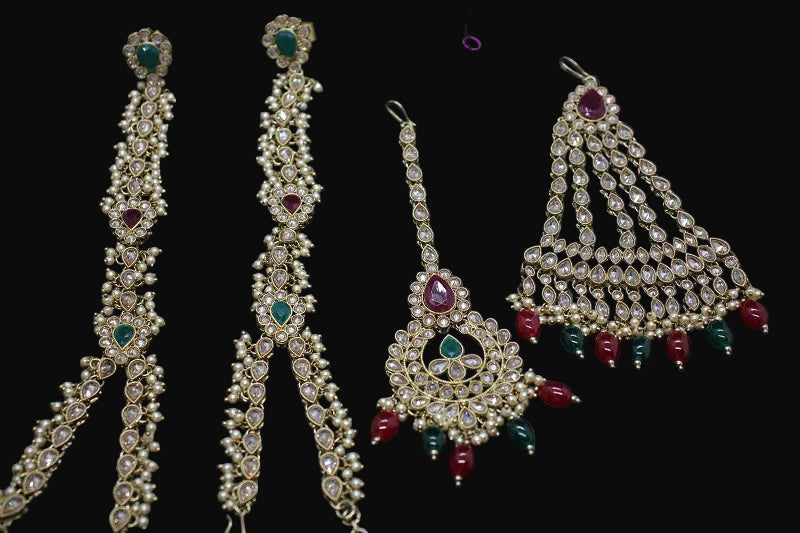 Set of gold jewelry with red and green stones on a dark background, featuring the brand 'Saheli'.