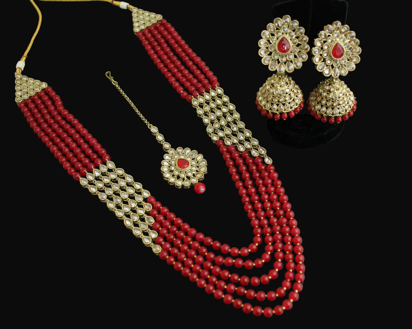 Red beaded necklace with gold accents and matching earrings on a dark background
